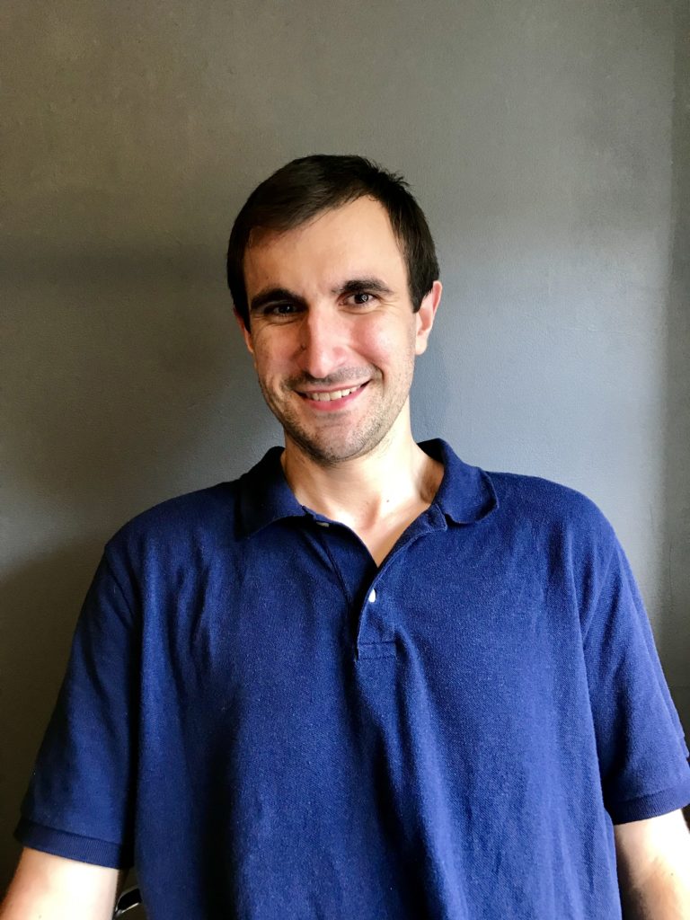 developer in chair smiling with blue shirt.